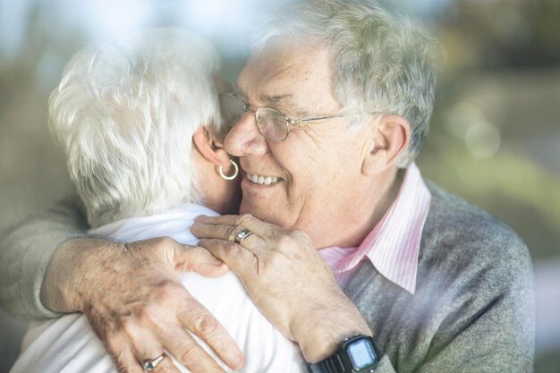 Photo happy senior couple hugging derrière la vitre