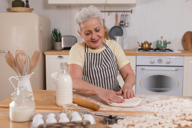 Happy senior woman cooking in kitchen élégant mature dame aux cheveux gris grand-mère pétrir la pâte