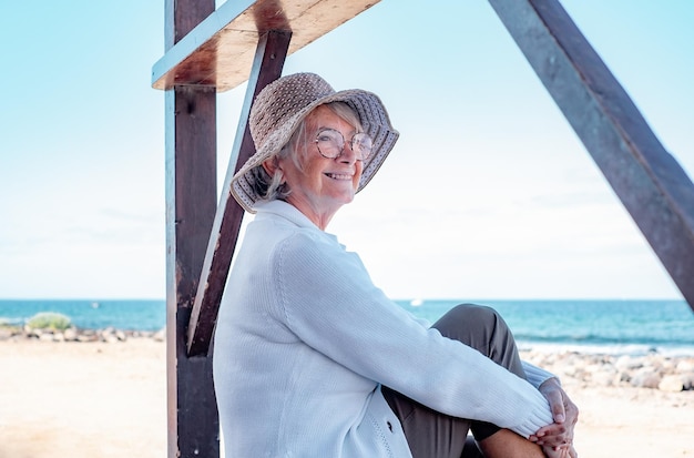 Happy senior woman sitting détendu à la plage à la voiture en profitant des vacances et de la liberté