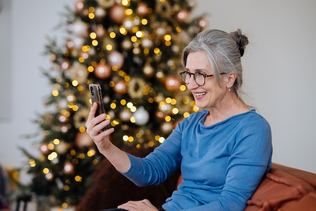 Happy smiley senior woman à l'aide de l'appel vidéo smartphone