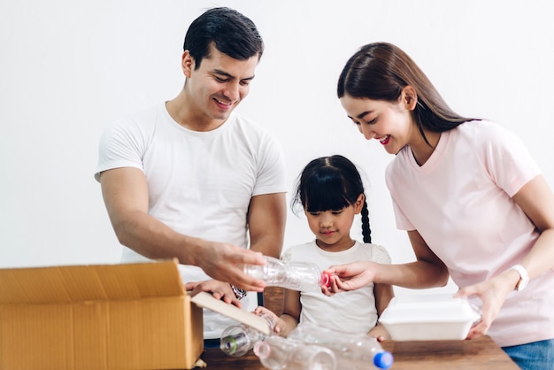 Happy smiling family having fun mettre des bouteilles en plastique de recyclage vides et du papier dans la boîte de recyclage