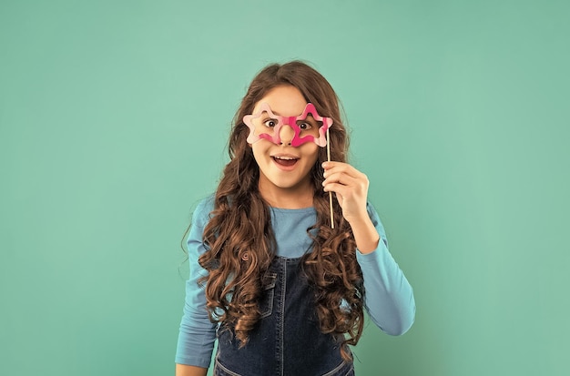 Happy teen girl a les cheveux bouclés tenir partie accessoire de lunettes enfance