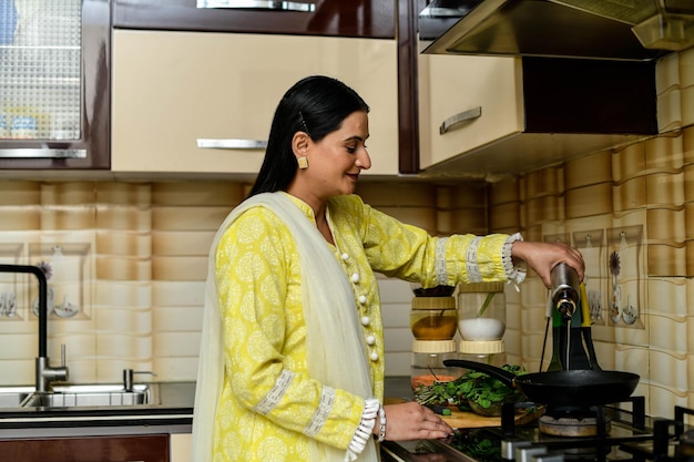 Happy woman cooking dans sa cuisine modèle pakistanais indien