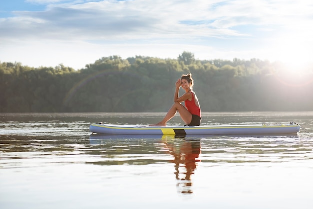 Happy woman sitting in paddle board dans une journée ensoleillée