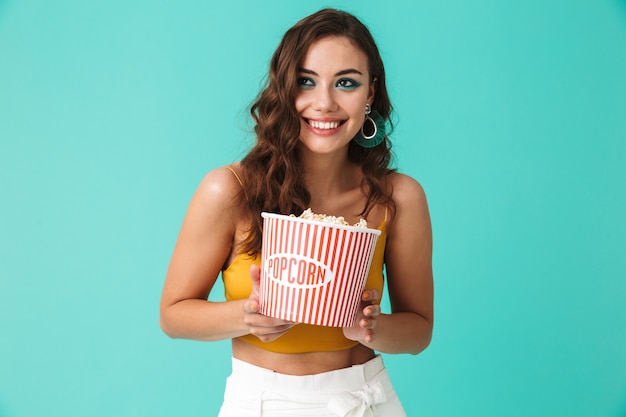 Happy woman wearing fashion earrings holding bucket avec pop-corn et souriant