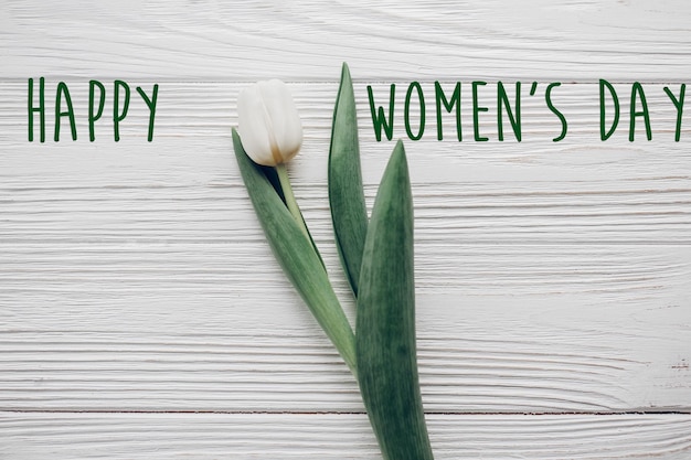 Photo happy women's day texte signe tulipe blanche élégante sur fond de table en bois rustique vue de dessus bonjour printemps plat poser lumière douce minimaliste