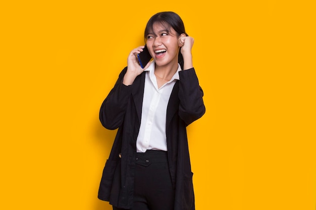 Happy young asian business woman using mobile phone isolé sur fond jaune