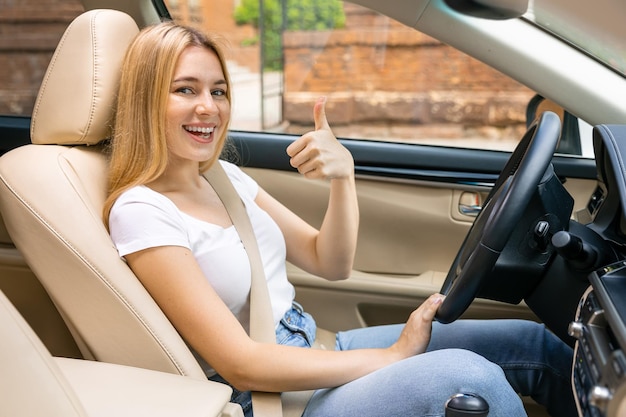 Happy young woman doing thumpsup en voiture sur route