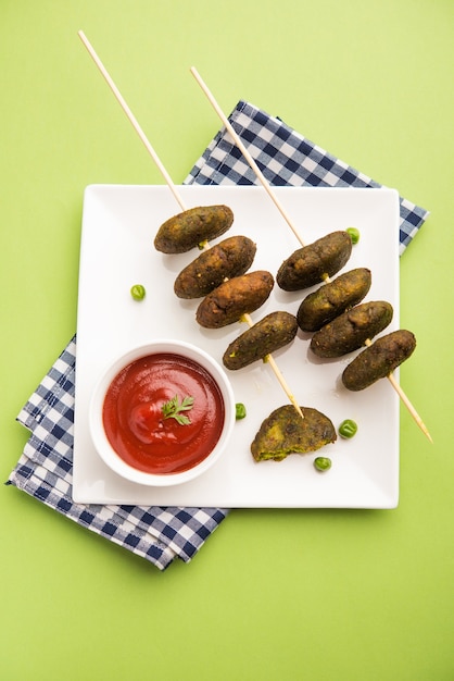 Hara Bhara Kabab ou Green Peas Pakora, entrée indienne populaire servie dans une assiette avec Chutney de tomates et de menthe sur fond de mauvaise humeur. Mise au point sélective