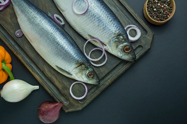 Hareng salé avec des oignons et des herbes sur une planche à découper