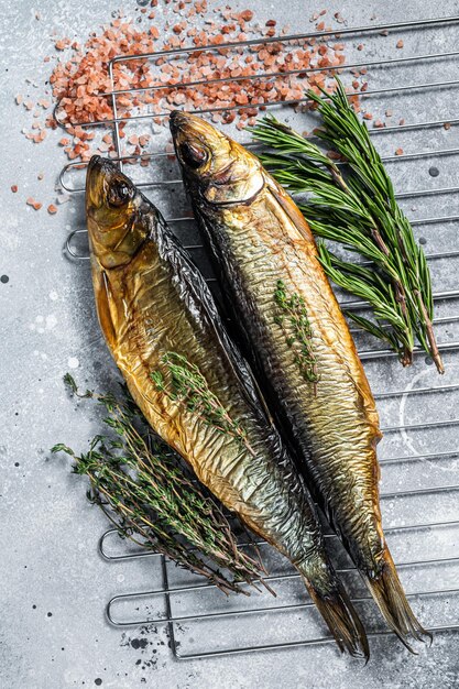 Harengs entiers fumés au kipper sur grill fumoir. Fond gris. Vue de dessus.