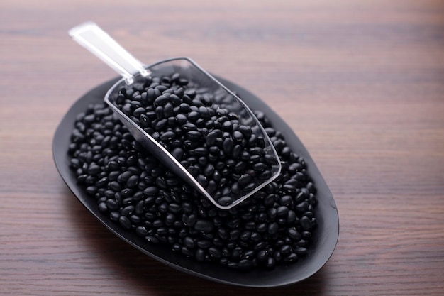 Photo haricot noir sur table en bois et cuillère en plastique ingrédient nutritionnel protéique pour végétarien