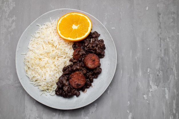 Haricots alimentaires brésiliens typiques avec saucisses et riz Feijoada sur plat blanc