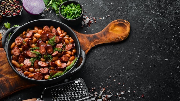 Haricots aux saucisses à la sauce tomate sur une plaque noire Vue de dessus Espace libre pour votre texte