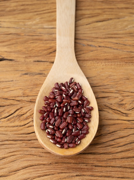 Haricots azuki dans une cuillère sur une table en bois.