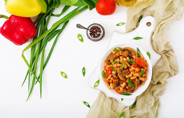 Photo haricots blancs cuits avec champignons et tomates avec sauce épicée dans un bol blanc. vue de dessus plat poser