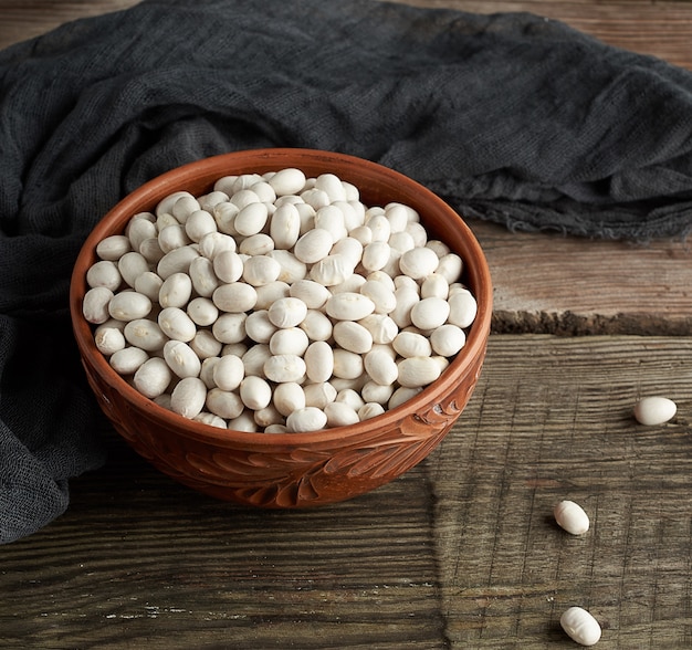 Haricots blancs ronds crus dans une assiette sur une table en bois