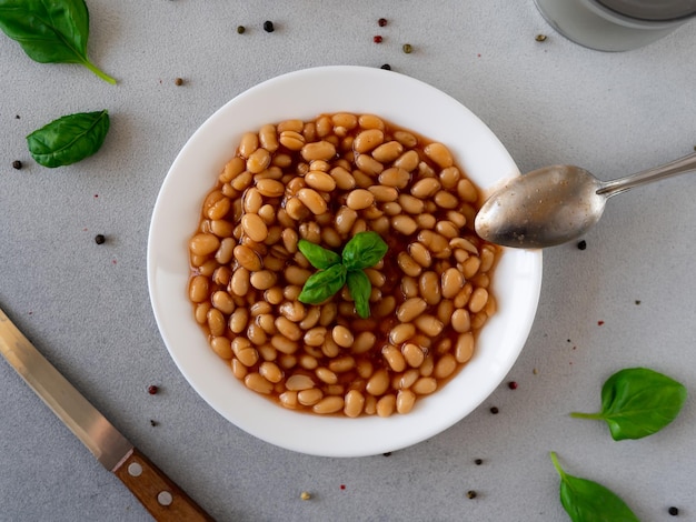 Photo haricots cuits au four à la sauce tomate dans une assiette sur un fond gris