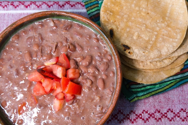 Haricots cuits dans un plat en argile avec tomate et tortillas plat pauvre mexicain