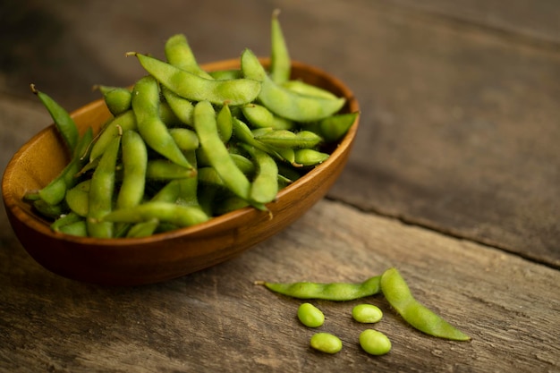 Des haricots d'edamame dans un bol en bois sur une table en bois texturé