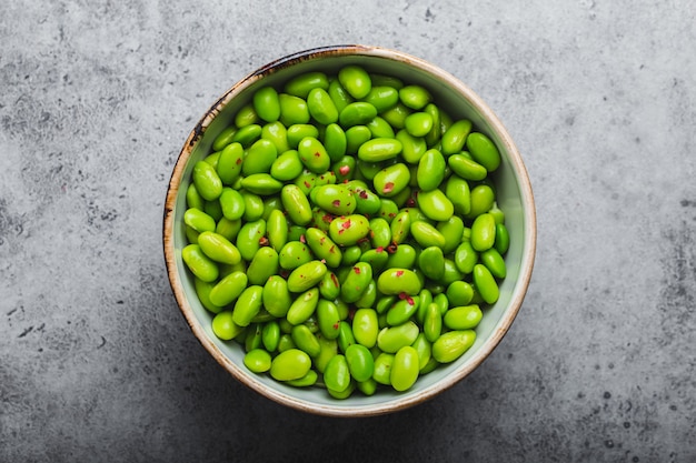 Haricots edamame verts mûrs frais sans gousses dans un bol sur fond de pierre grise. Vue de dessus, gros plan. Collation asiatique légère et saine bonne source de protéines végétariennes pour l'alimentation et la nutrition