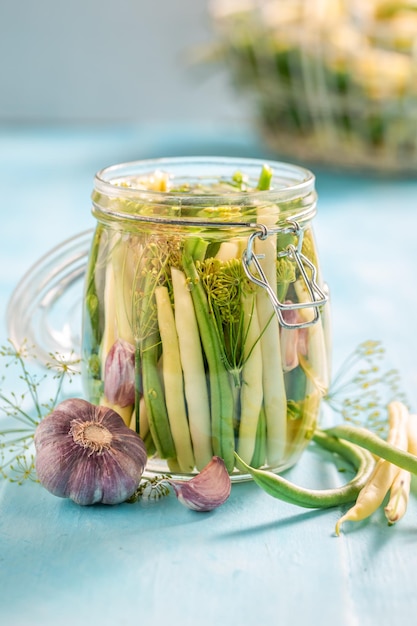 Haricots jaunes et verts marinés sains dans un bocal avec des herbes