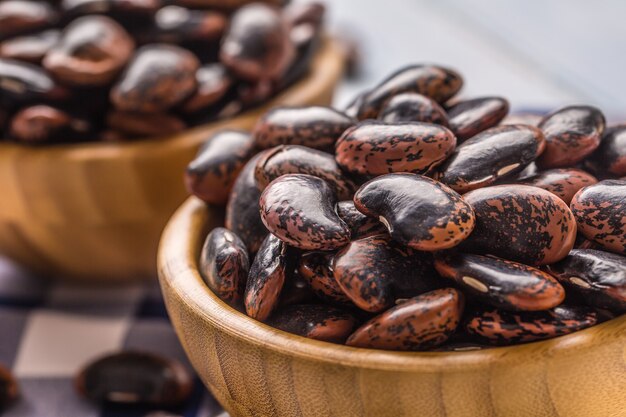 Haricots non cuits dans des bols en bois sur la table de la cuisine.