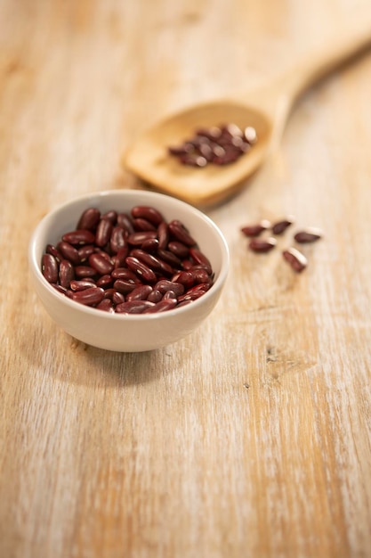 Haricots rouges dans une cuillère et dans un bol sur fond de bois