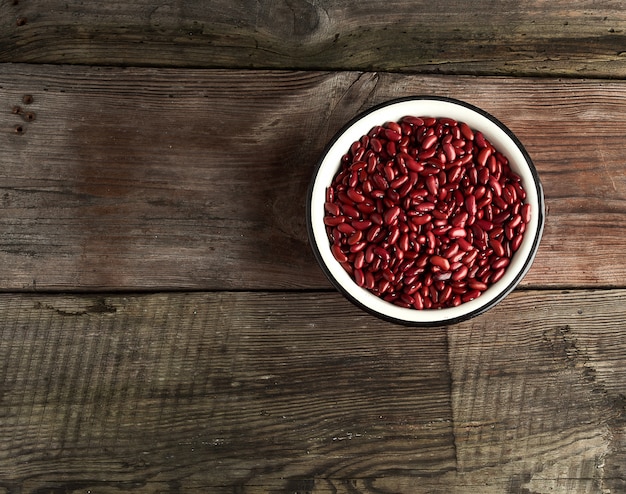 Haricots rouges ovales crus dans une assiette sur une table en bois