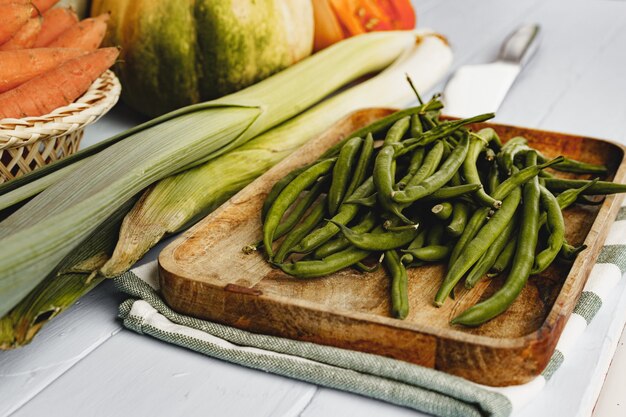 Haricots verts dans une assiette et autres légumes sur la table de cuisine