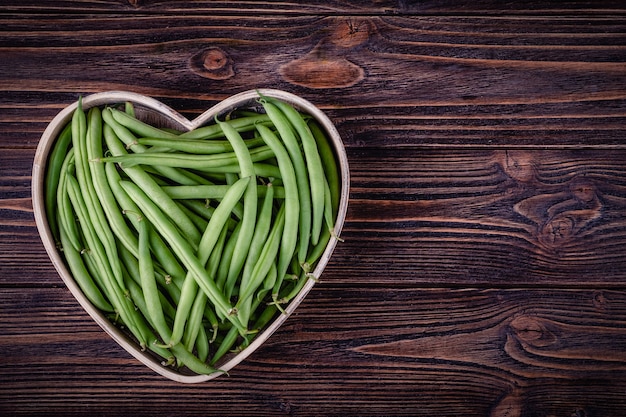 Haricots verts frais sur table en bois sur fond de bois rustique.