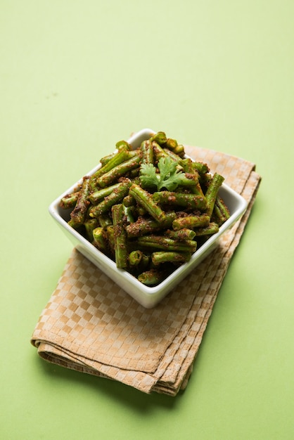 Haricots verts Masala curry sec, recette de légumes indiens servis dans un bol carré sur fond coloré, mise au point sélective