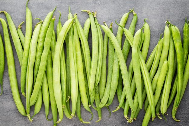 Haricots verts sur une surface grise.