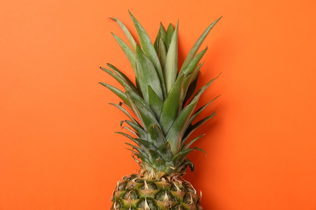 Haut d'ananas sur fond orange, espace pour le texte. Fruit juteux