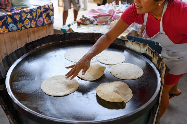 D'en haut, une cuisinière mexicaine méconnaissable met de la pâte sur une plaque chauffante chaude tout en cuisant de délicieux pains plats chapati dans la rue