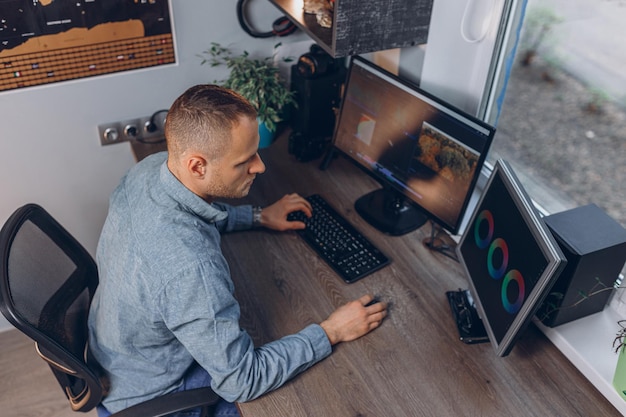 D'en haut d'un éditeur vidéo faisant un montage sur ordinateur à l'aide d'un logiciel professionnel dans un bureau à domicile