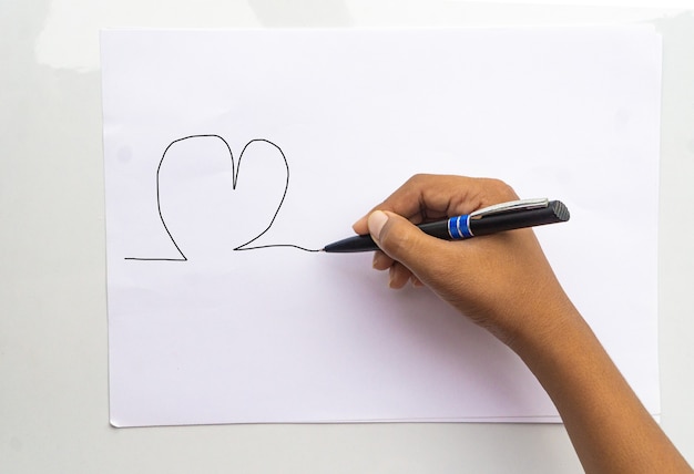 Haut en gros plan au-dessus de la vue aérienne photo d'un enfant de la main droite tenant un stylo en bois commençant à dessiner une image isolée sur fond de couleur papier blanc