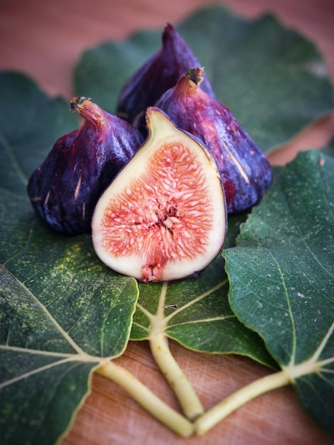 D'en haut, gros plan de fruits exotiques moelleux à croûte violette placés sur des feuilles vertes empilées