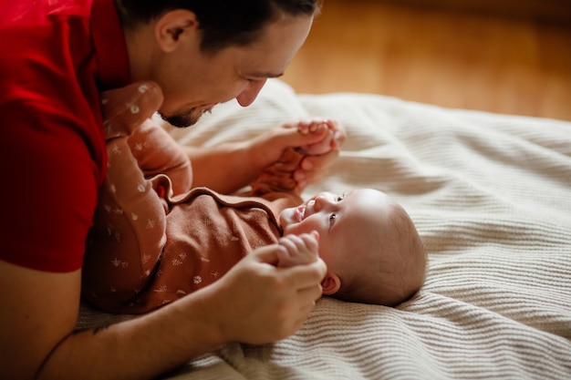 D'en haut heureux homme barbu jouant et parlant avec un bébé mignon sur un lit confortable à la maison