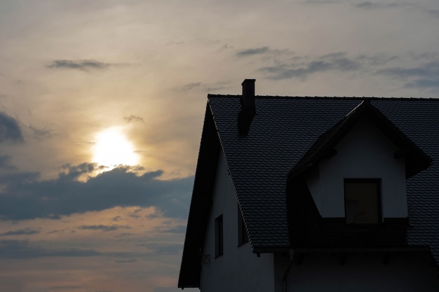 Photo haut de la maison avec toit et mezzanine au coucher du soleil.
