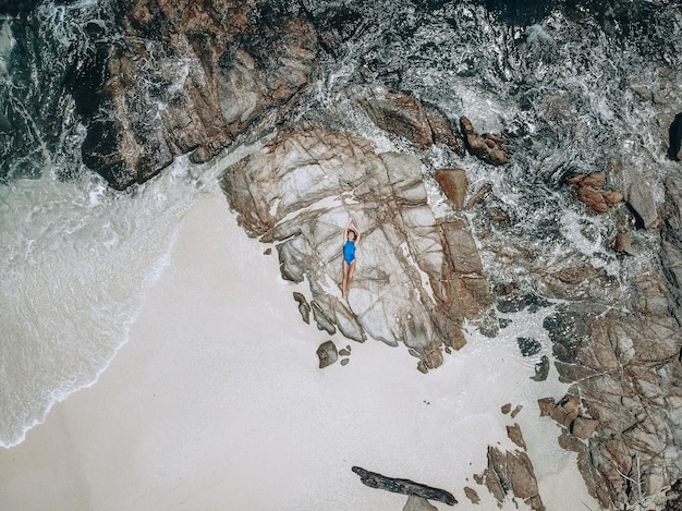 D'en haut photo d'une jolie jeune femme en maillot de bain bleu allongé sur le rocher à marée haute. Concept de vacances d'été