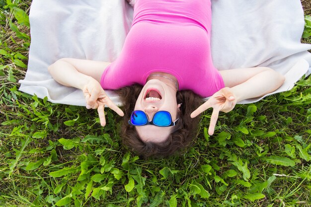 Haut portrait de drôle de jeune femme allongée sur l'herbe dans le parc