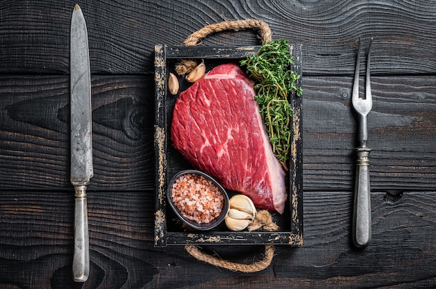 Haut de surlonge cru de boeuf coupé steak de viande ou Picanha dans un plateau en bois avec des herbes