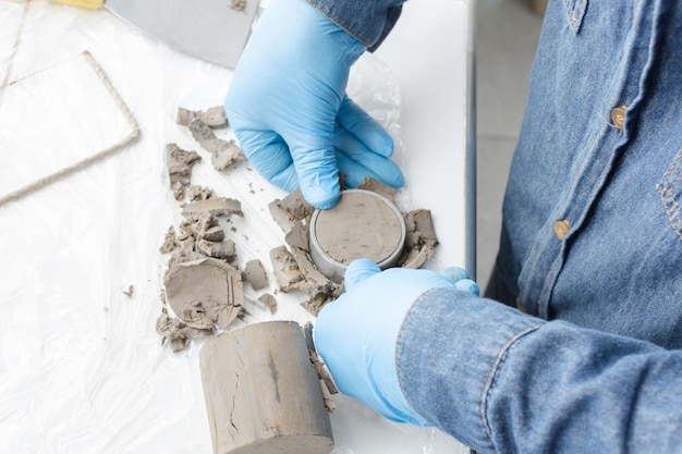 Haut de la vue des mains avec des gants en latex bleu appuyant sur un anneau métallique pour couper l'argile circulaire pour faire des tests de laboratoire