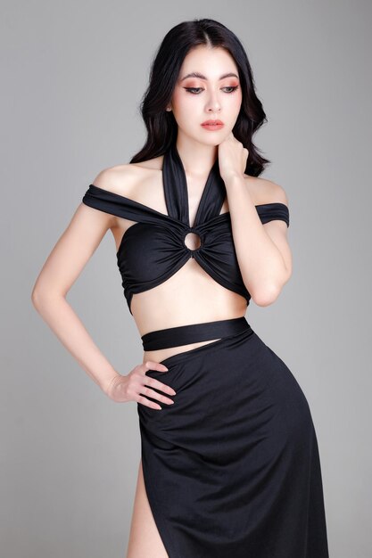 Haute couture de jeune femme élégante confiante portant une robe sexy noire à la mode avec un corps parfait posant sur fond blanc Copier l'espace vide Maquillage