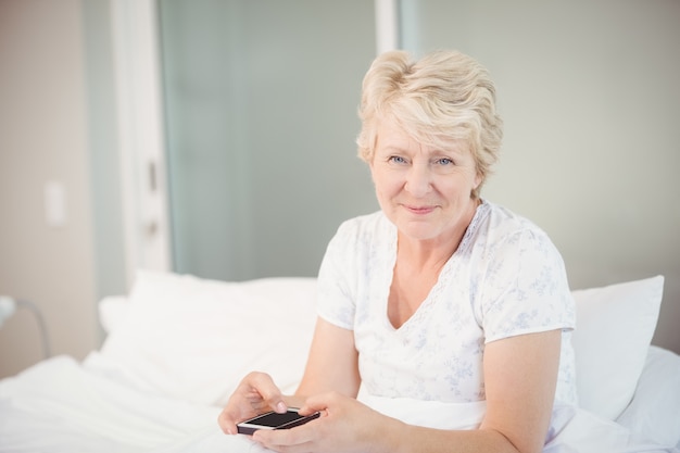 Haute femme à l'aide de téléphone au lit