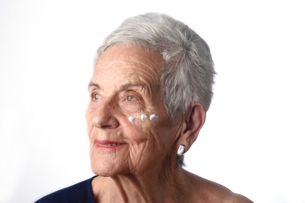 Haute femme appliquant une crème pour la peau ou un hydratant sur son visage