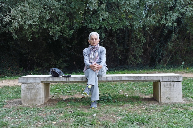 Haute femme assise seule sur un banc dans un parc