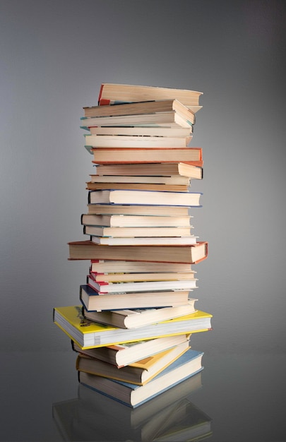 Haute pile de livres sur la table dans le contexte d'un mur gris