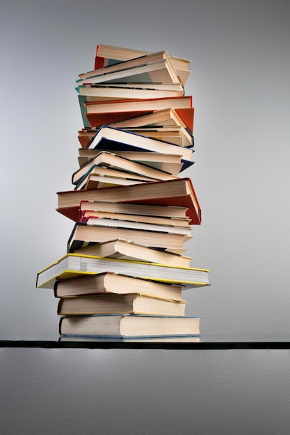 Haute pile de livres sur la table sur fond de mur gris